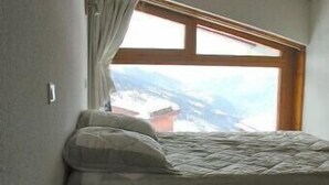 A bedroom with a bed, a window with curtains, and a view of a snowy landscape. - ARCS1800 very sunny 3 rooms 3 shower rooms balcony 50m Transarc and shops (Bourg-Saint-Maurice)