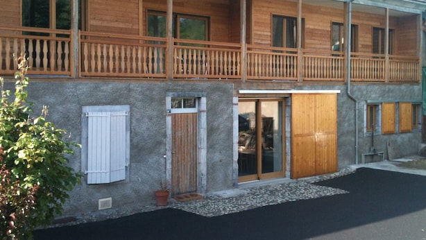 Un bâtiment à deux étages doté de balcons en bois, de grandes fenêtres et d’une façade en pierre.