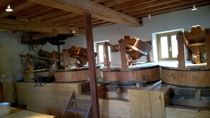 Un intérieur rustique avec des éléments en bois apparents, notamment des poutres, un escalier en bois et une grande fenêtre laissant entrer la lumière naturelle.