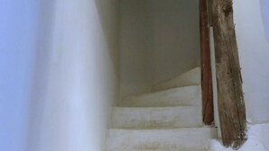 A staircase with white steps leading upwards, wooden handrails, and framed pictures on the wall.