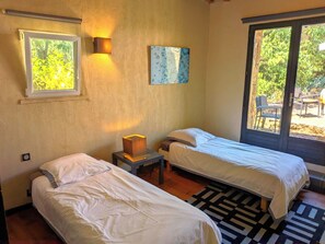 A room with two beds, a window with a view of greenery, a wall-mounted lamp, and a painting. - Private pool10X5, 11 bedr., 26 beds, 5 bath., 5 terraces, very quiet,10 000sqm park,AC (Uzès)