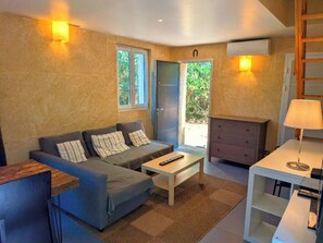 Un espace de vie compact comprenant un canapé, une table basse, une commode et une lampe.