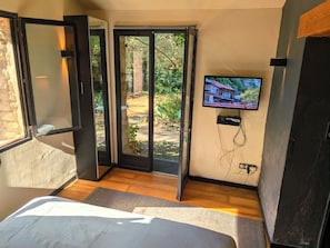 A bedroom with a bed, a television, and a sliding glass door leading to an outdoor area.