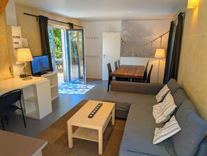 Una sala de estar moderna con un sofá, una mesa de centro, un televisor y un comedor con una mesa y sillas.