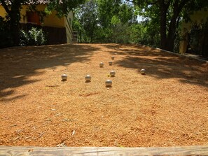 A courtyard with a wooden fence, a sandy ground, and several spherical objects.