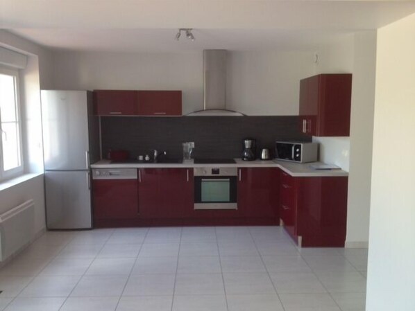 Una cocina moderna con armarios rojos, un refrigerador de acero inoxidable, un microondas y un lavavajillas.