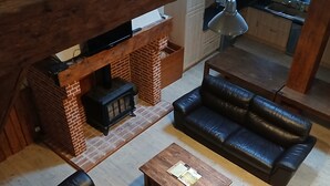 Un espace de vie de style loft avec une cheminée en briques, des canapés en cuir et une table basse en bois.