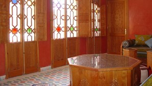Une pièce dotée d’un sol à carreaux, de meubles en bois et de portes richement décorées de motifs géométriques.