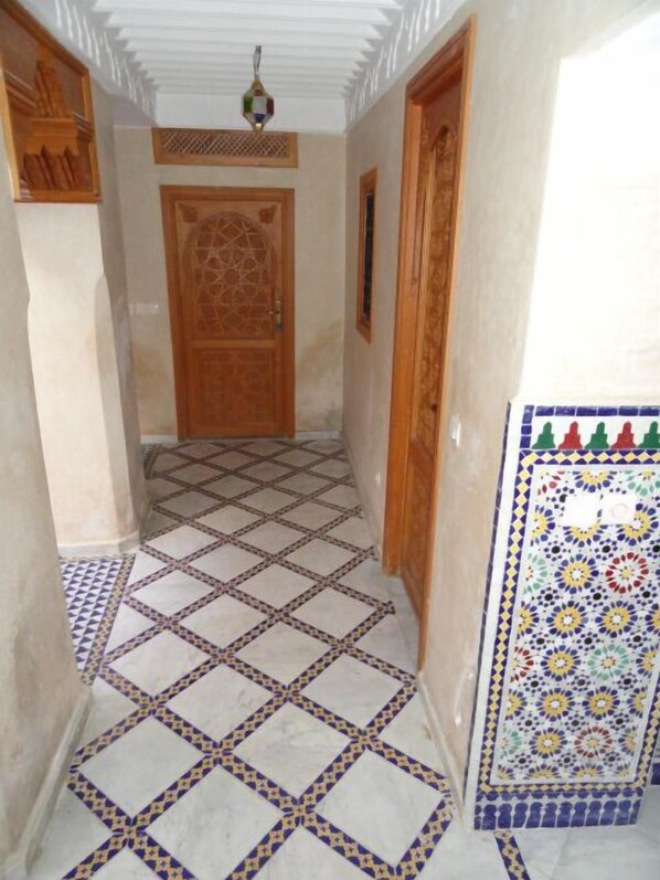 A hallway with patterned floor tiles, a wooden door, and a decorative ceiling light. - Authentic riad - Exclusive - Marrakech Medina (Marrakech)