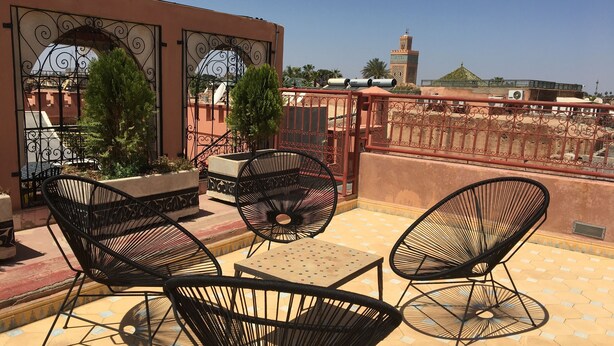 Une terrasse avec des sièges extérieurs, une vue sur une mosquée et une porte décorative.