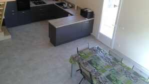 A modern kitchen with dark cabinetry, a central island, and a dining area with a table set for four.