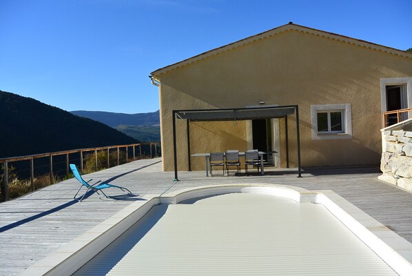 A house with a swimming pool, outdoor seating, and a mountain view.