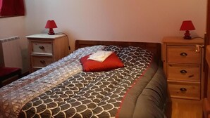 Une chambre à coucher comprenant un lit, deux tables de chevet, une commode et un luminaire au plafond.