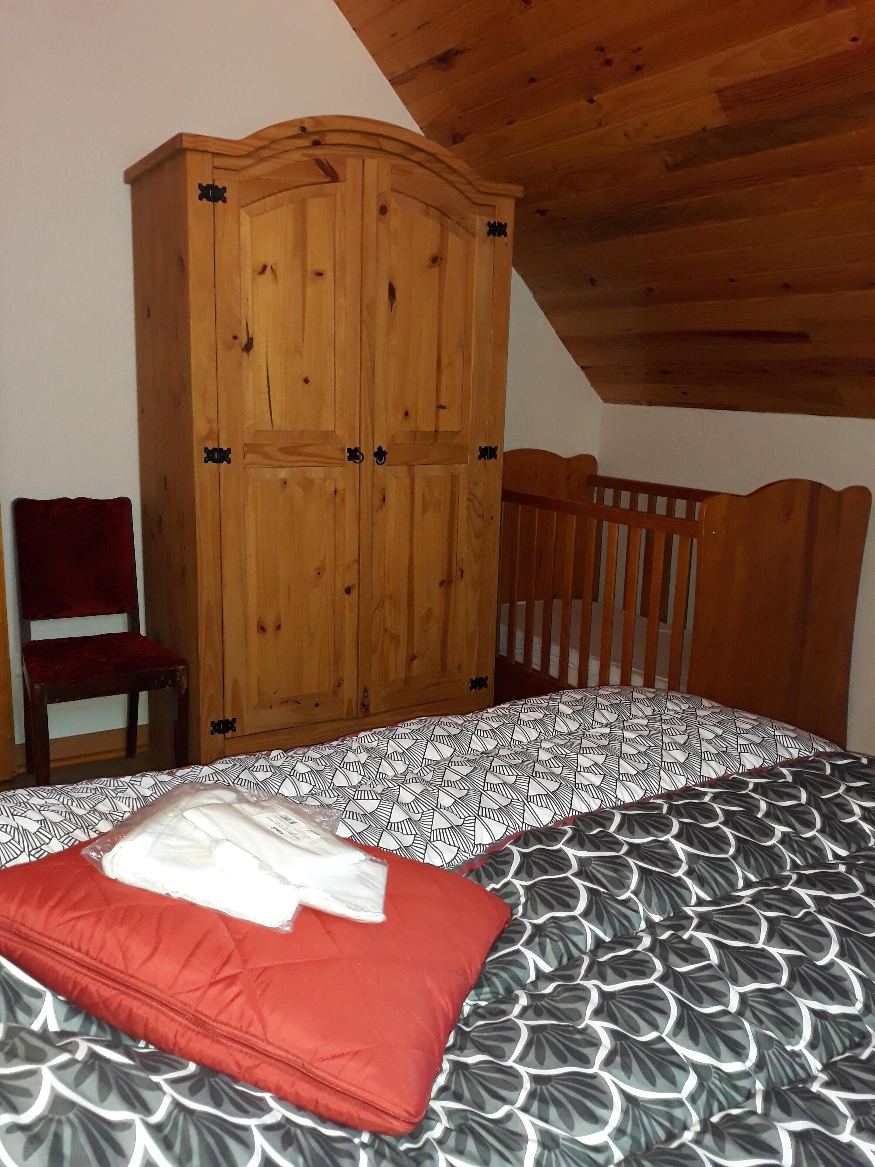 Una camera da letto con un'armadiatura in legno, una sedia in legno e un letto con biancheria decorata.