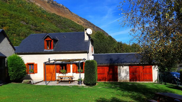 Une maison avec un toit en pente, une antenne parabolique et une grange rouge.