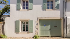 A two-story building with green shutters, a green door, and a visible no parking sign. - Island of Re. House near sandy beach, harbor and shops (La Flotte)