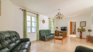 A living room with a green sofa, a wooden coffee table, and a television. - Island of Re. House near sandy beach, harbor and shops (La Flotte)