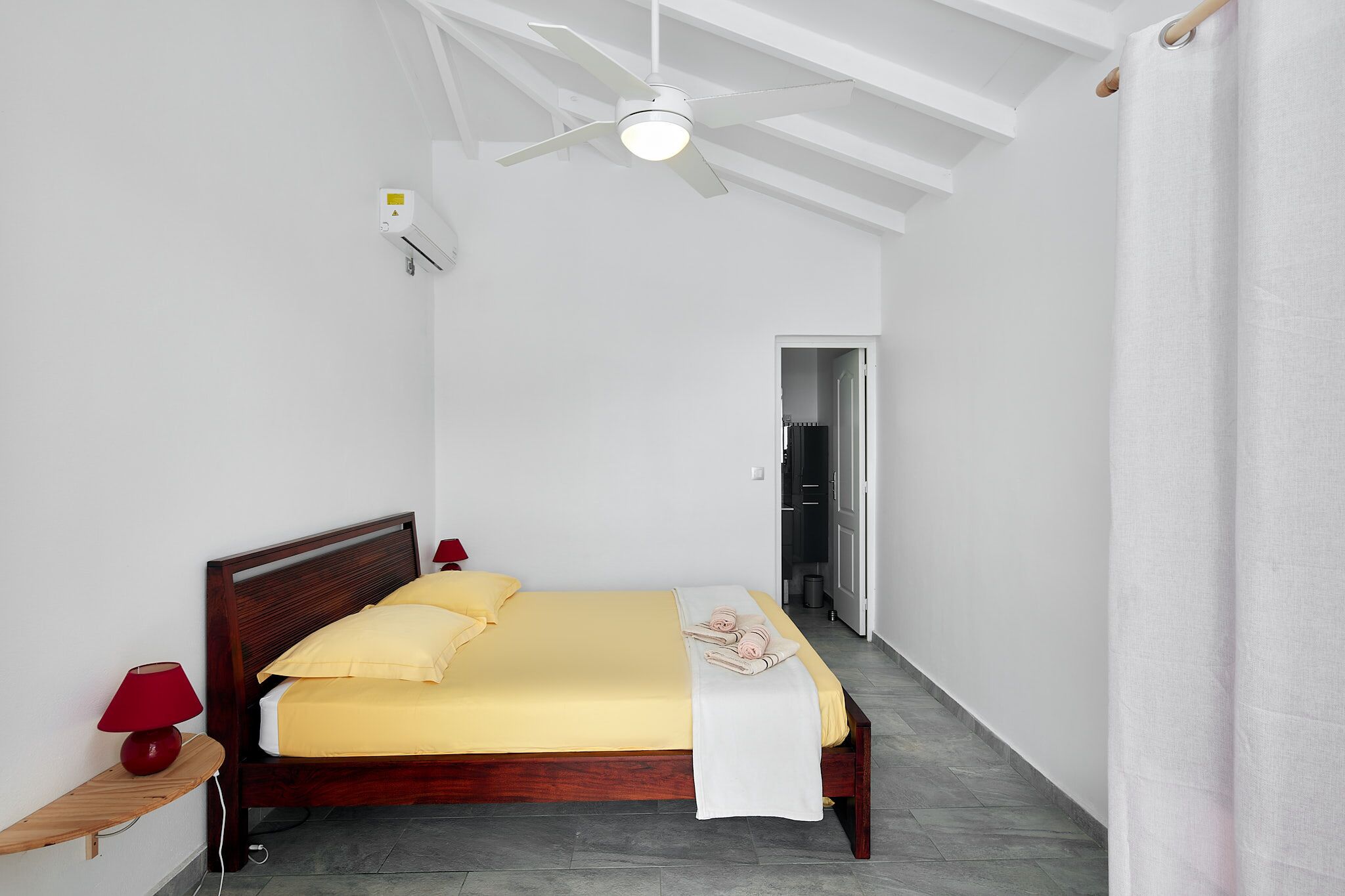 A bedroom with a wooden bed, a ceiling fan, and a nightstand with a lamp.