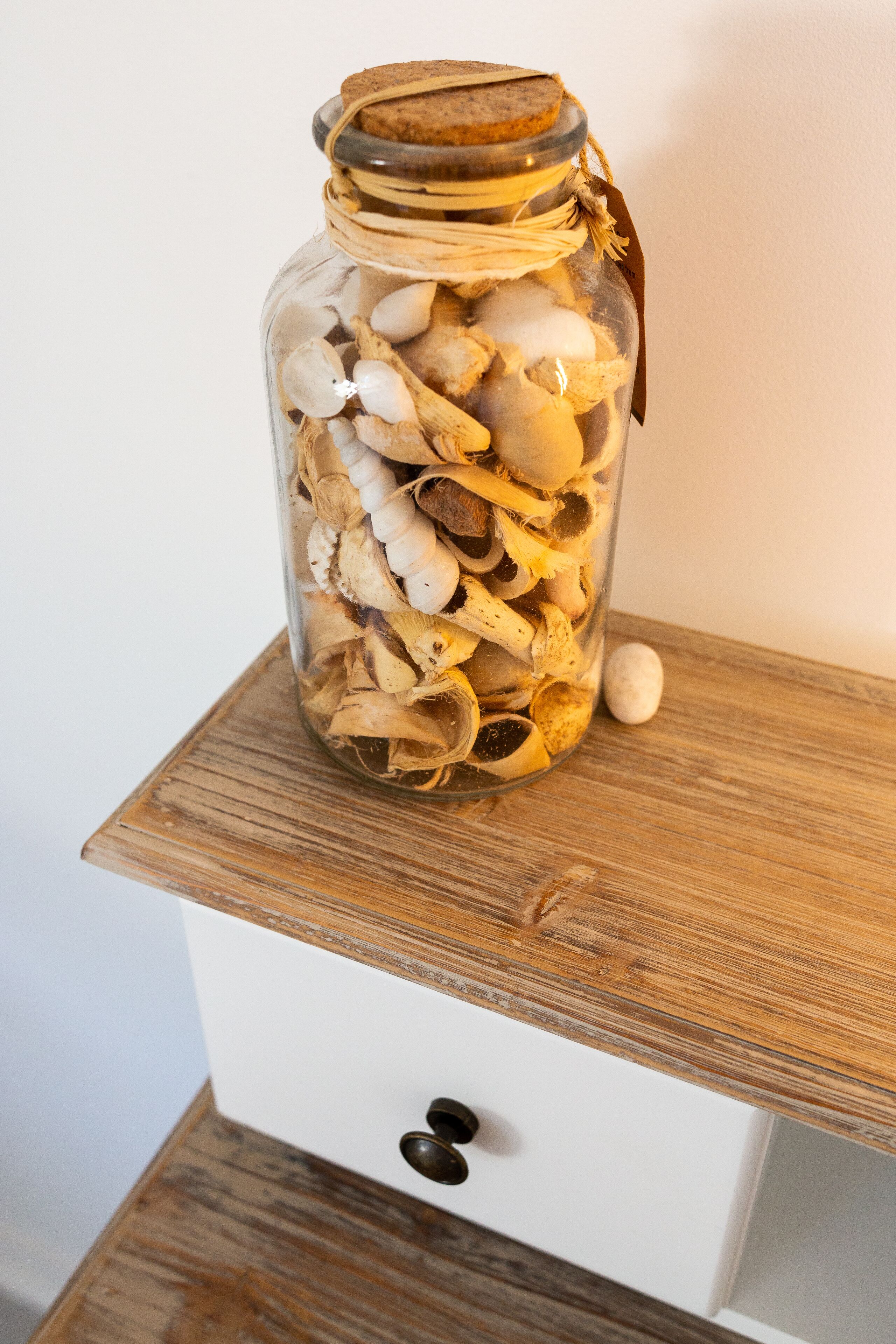 Ein Glasgefäß, gefüllt mit getrockneten Pilzen auf einer Holztischfläche.