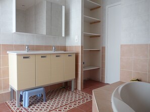 A bathroom with a beige vanity, two sinks, a mirror, a bathtub, and a patterned floor. - New house in Piriac sur mer, small town of character by the sea (Piriac-Sur-Mer)