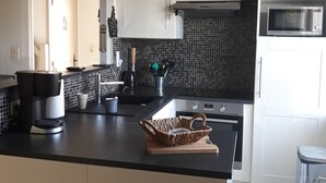 A modern kitchen with white cabinets, a black countertop, a microwave, and a coffee maker. - THE FLEET IN RE classified ** (La Flotte)