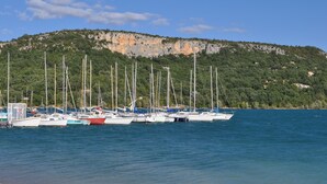 A marina with several sailboats docked, a rocky hillside in the background, and calm water. - With view on the lake of Ste Croix, contemporary villa for 8 people  (Bauduen)