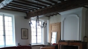 A traditional living room with leather sofas, a wooden coffee table, a fireplace, and a chandelier. - Gite in Normandy with private and heated swimming pool. (Bacqueville-En-Caux)