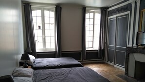 A hotel room with two beds, a desk with a lamp, and a large window with curtains. - Gite in Normandy with private and heated swimming pool. (Bacqueville-En-Caux)