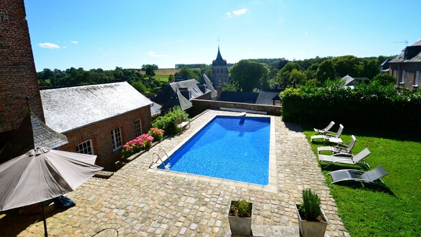 A rectangular swimming pool with a stone deck, surrounded by lounge chairs and potted plants. - Gite in Normandy with private and heated swimming pool. (Bacqueville-En-Caux)