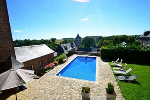 A rectangular swimming pool with a stone deck, surrounded by lounge chairs and potted plants. - Gite in Normandy with private and heated swimming pool. (Bacqueville-En-Caux)