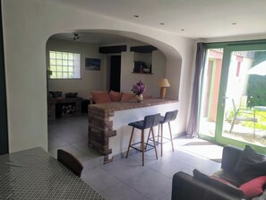 Una cocina moderna con una isla central, taburetes de bar y una zona de comedor con mesa y sillas.