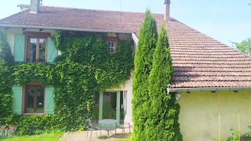 A house with a tiled roof, a chimney, and a green ivy-covered wall.