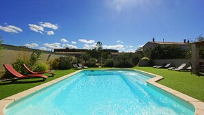 Una piscina rettangolare con bordi piastrellati, circondata da un prato con diversi lettini.