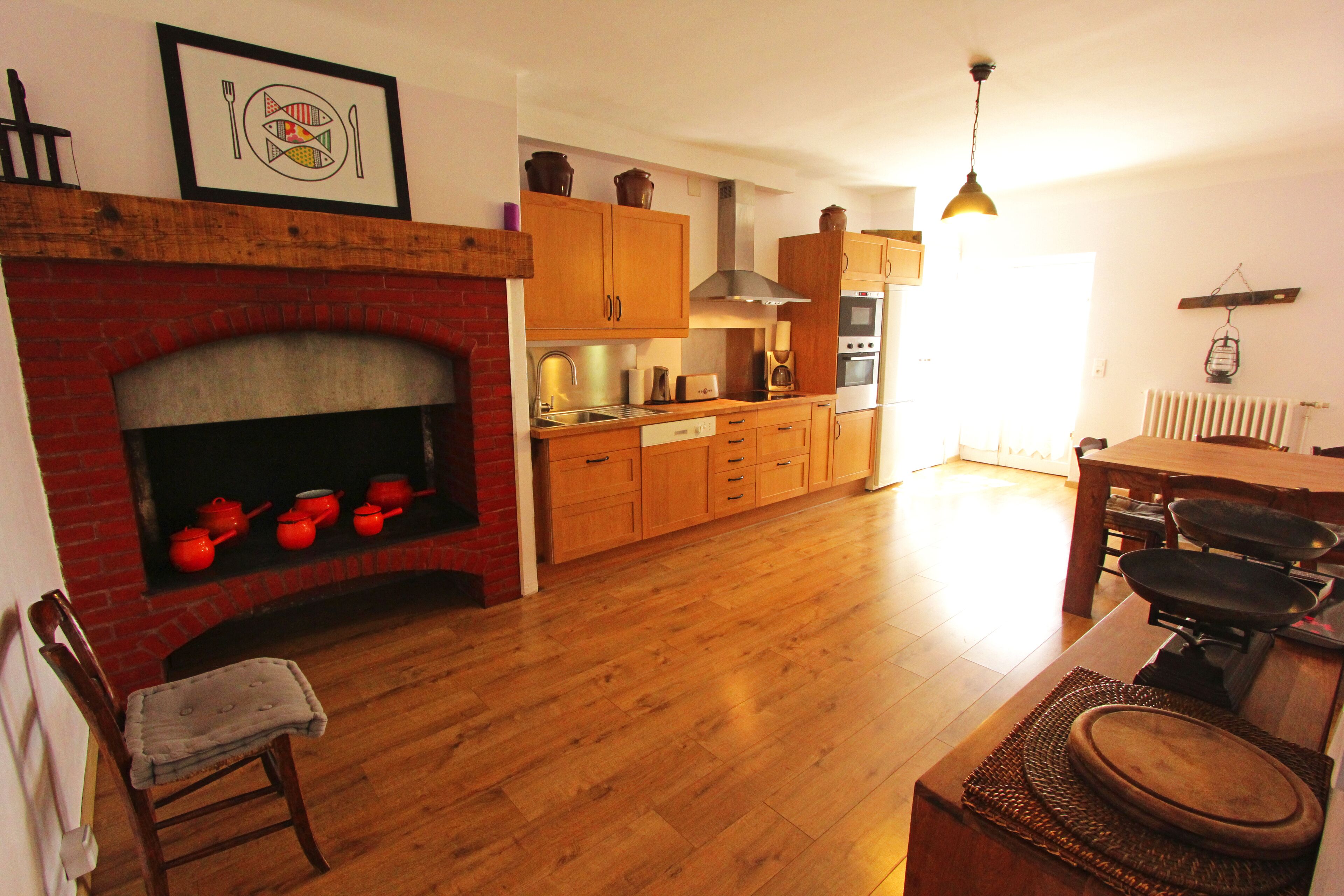 A spacious kitchen with wooden cabinets, a brick fireplace, and a dining area with a table and chairs.