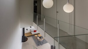 Interior moderno com claraboia, guarda-corpo de vidro e iluminação pendente.