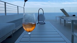 Um copo de vinho em um terraço com vista para o oceano.