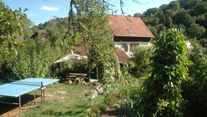 Una casa con tetto in tegole rosse, immersa nel verde e circondata da un giardino.