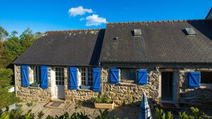 Un bâtiment en pierre avec un toit de tuiles, des murs en pierre et des volets bleus.