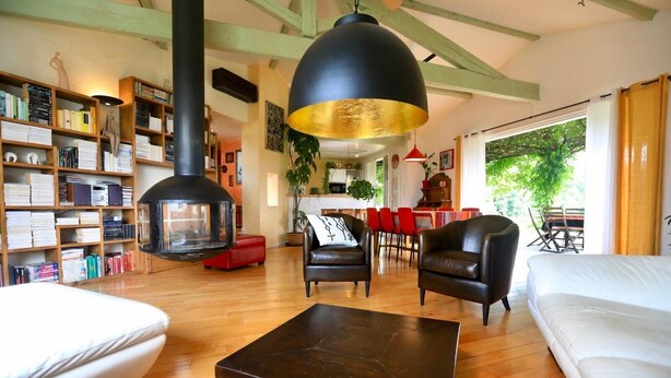 A cozy living room with a fireplace, leather sofas, a coffee table, and a bookshelf filled with books. - Mirepoix architect-designed villa bright heated pool gym wifi air-conditioning. (Roumengoux)