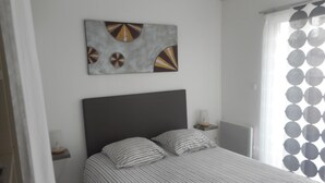 Une chambre à coucher comprenant un lit, une tête de lit, une table de chevet, une lampe et une œuvre d’art murale.