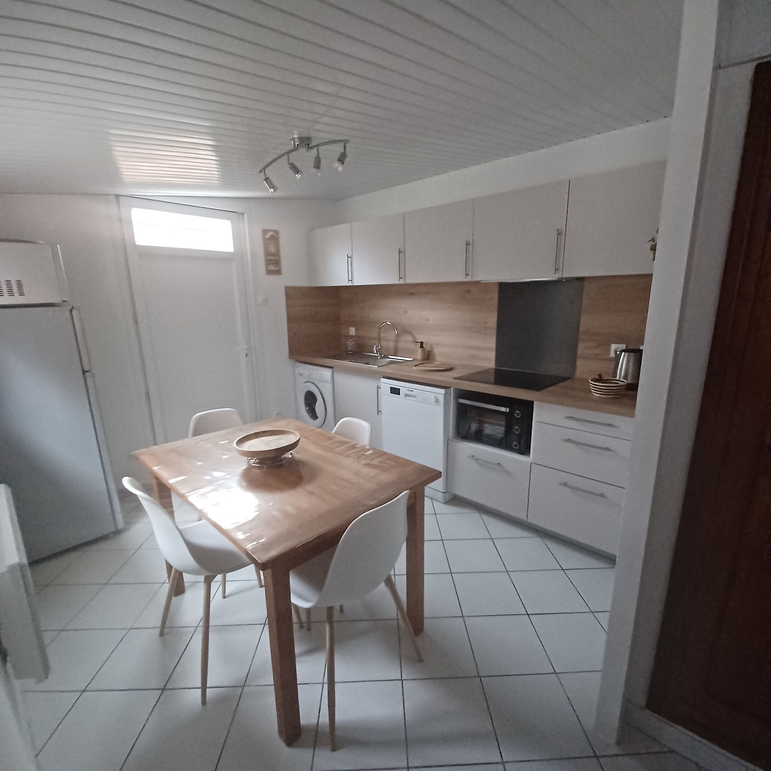 Una cucina compatta con mobili bianchi, un tavolo da pranzo in legno e un forno integrato.