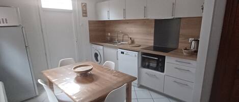 Una cucina compatta con mobili bianchi, un tavolo da pranzo in legno e un forno integrato.
