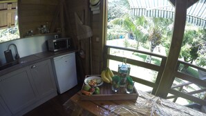 Una cocina con microondas, lavamanos y ventana con vistas a un jardín.