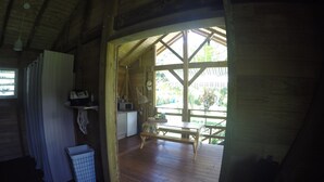 Una cabaña de madera con zona de cocina, una mesa de comedor y vistas al exterior.