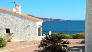 A coastal building with a white exterior and a red roof, overlooking the sea. There are potted plants in the foreground. - Renovated villa with exceptional panoramic view (Banyuls-Sur-Mer)