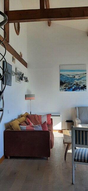 A living room with a brown sofa, a striped chair, a painting, and a lamp.