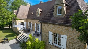 Un bâtiment en pierre doté d’un patio, d’un espace extérieur aménagé avec des sièges et d’un petit escalier menant à l’entrée.