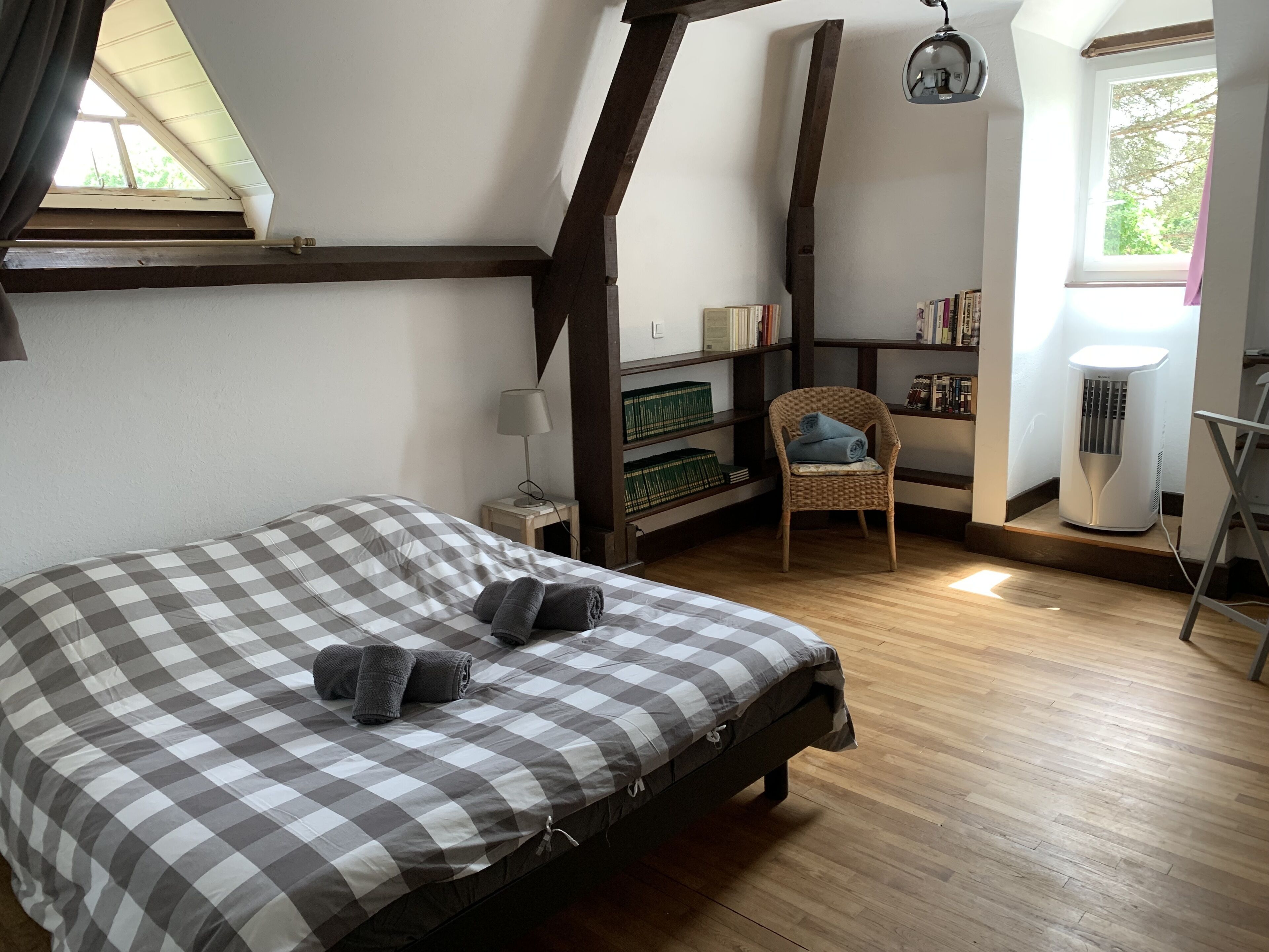 Un dormitorio con edredón a cuadros, una silla, una estantería y un radiador.