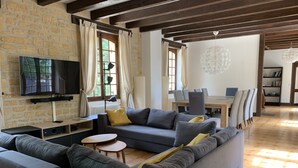 Un salon comprenant un canapé, un téléviseur et un coin repas avec des chaises et une table.