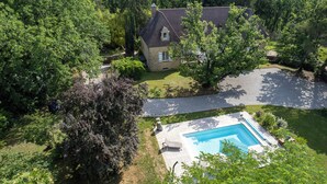 Une vue aérienne d’une maison avec une piscine, entourée d’une végétation luxuriante et dotée d’une allée.